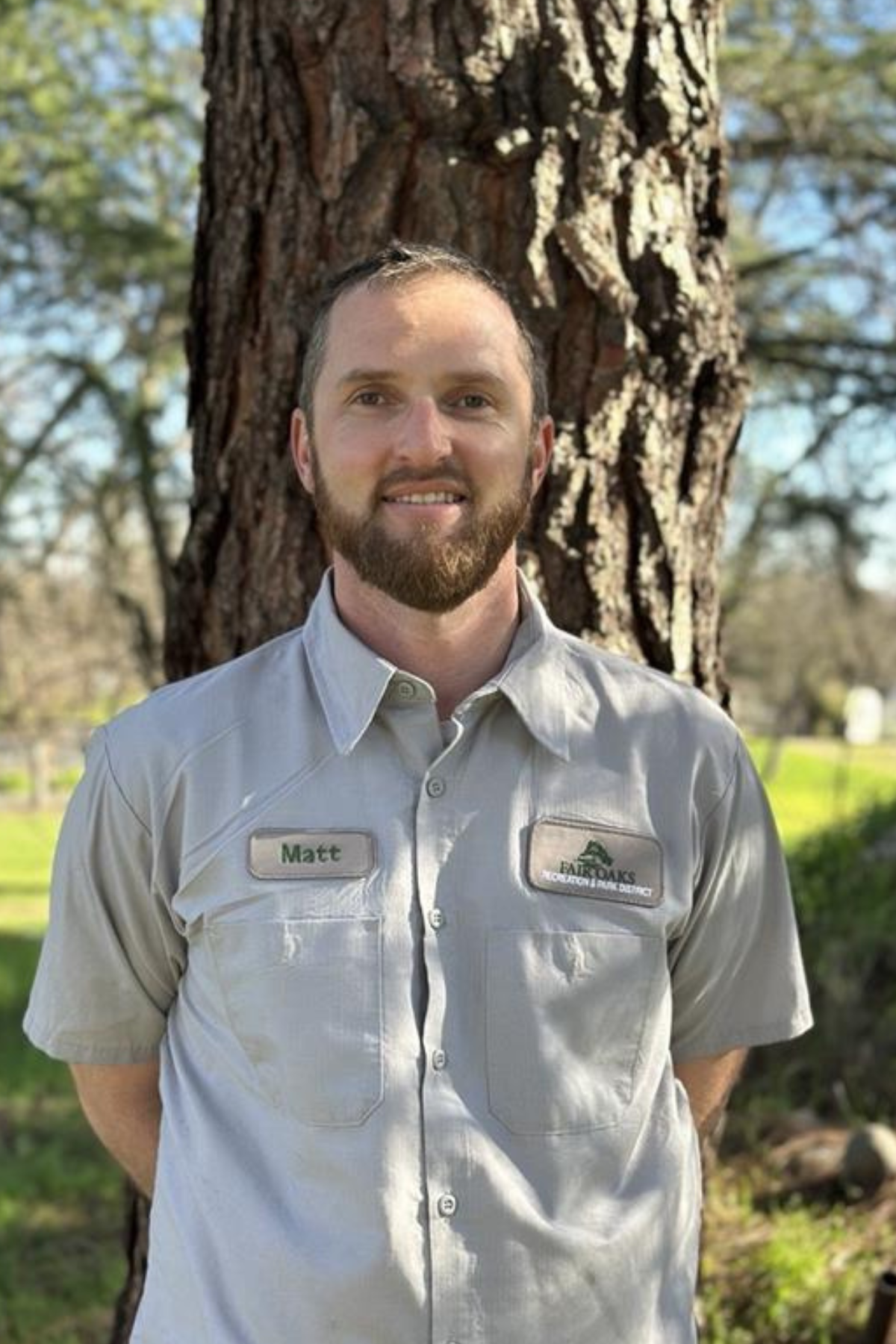 photo of a park worker standing in front of a tree